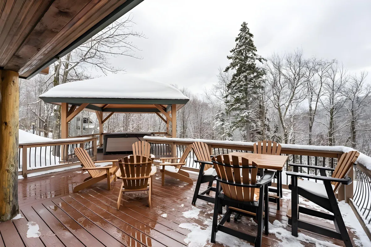 A spacious wooden deck with Adirondack chairs and a gazebo, all set against a backdrop of mountain scenery. The scene conveys a welcoming area for relaxing, socializing, or enjoying the natural surroundings. The outdoor elements suggest easy access to adventure and beautiful views.