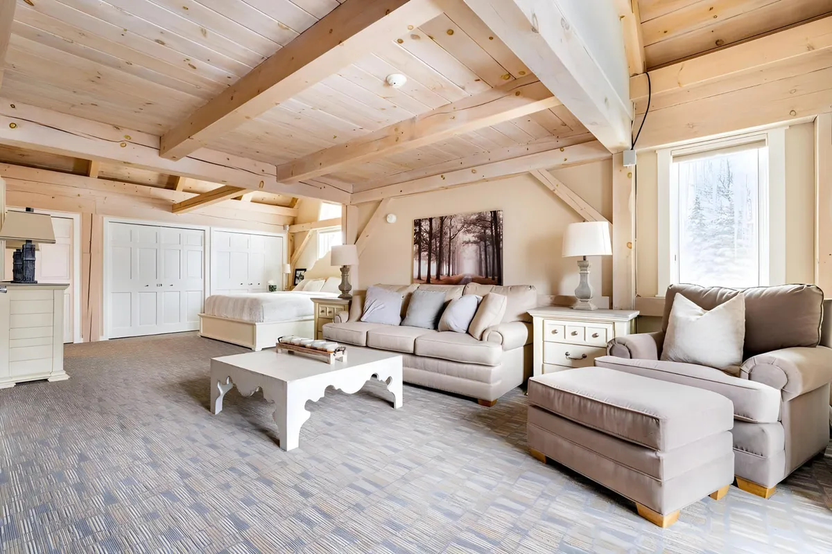 A welcoming living area featuring a comfortable sofa, coffee table, and large windows that fill the space with natural light. The layout is open and spacious, with artwork adding a cozy, homey touch. The room is designed for relaxation, socializing, and enjoying views of the outdoors.